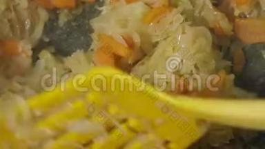 厨师用锅中的锅铲搅动胡萝卜和洋葱，并加入植物油